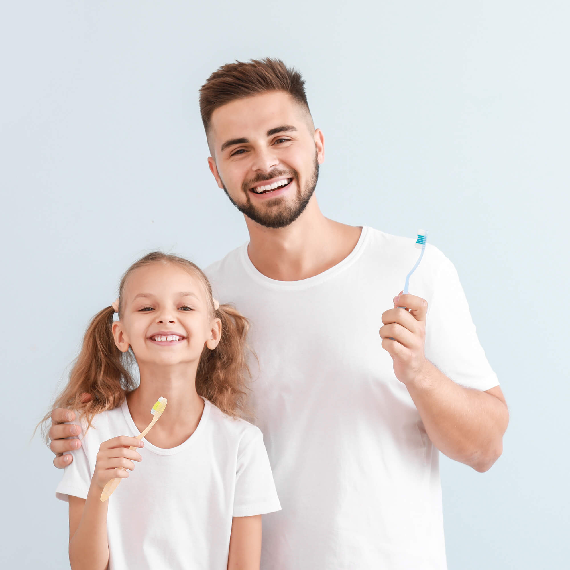 smiling dad and daughter stood holding toothbrushes