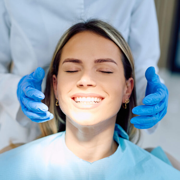 female sitting in dentist chair showing clean white teeth