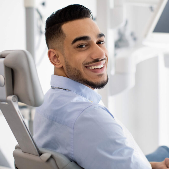 smiling man with clean white teeth sitting in a dentist chair