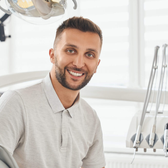 male sitting in dentist chair smiling at the camera